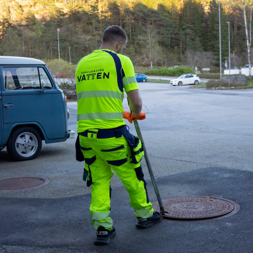 En rørlegger med ryggen snudd prøver å opne en rørsjakt.